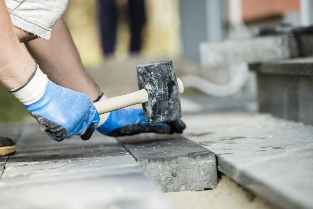 Workman laying a paving stone or brick